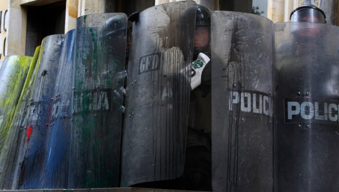 A group of police cover their bodies as an observes during a May Day march through the streets of Bogota, Thursday, May,1, 2008. (AP Photo/William Fernando Martinez)