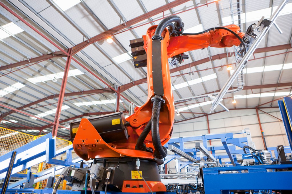 Robotic machinery lifting steel fencing on production line in manufacturing plant