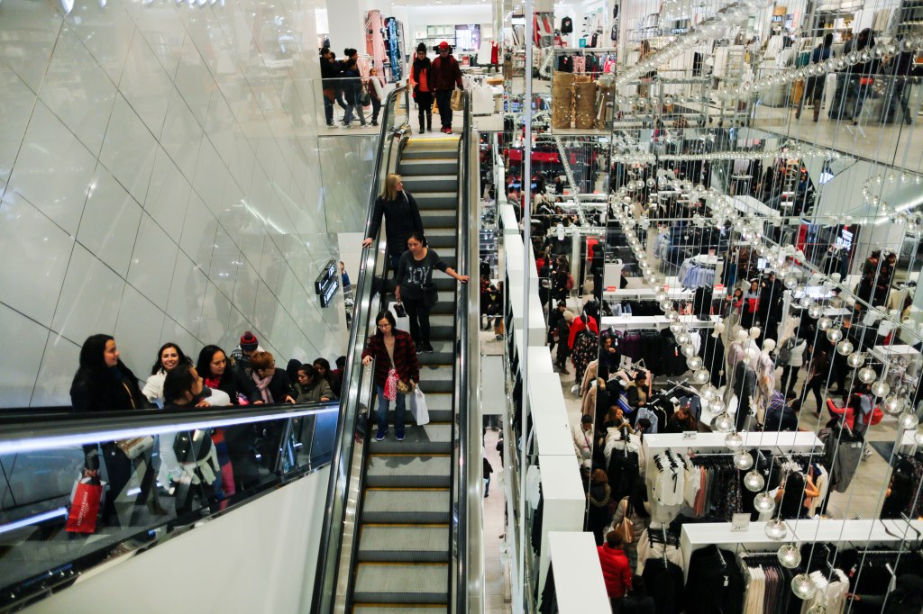 People ride an escalator inside an H&M retail store during Black Friday events