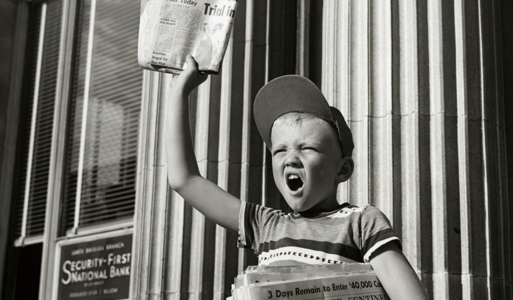 男孩在大楼前卖报纸