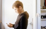 teenage boy in bedroom, looking at mobile phone