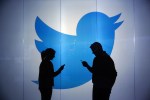 two people silhouetted in front of wall bearing Twitter logo
