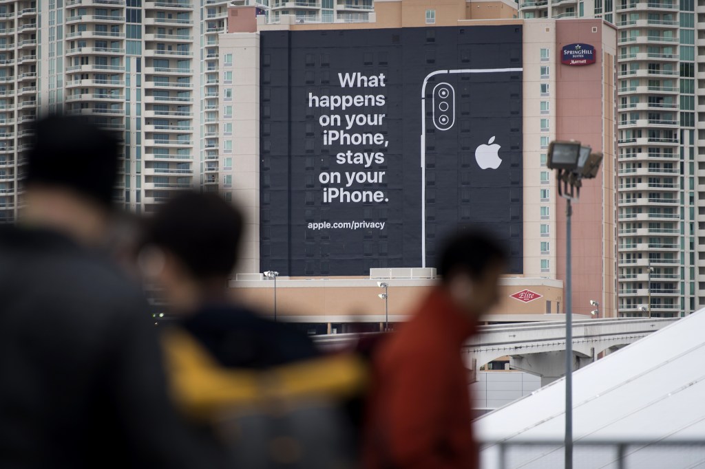 Pedestrians pass in front of a billboard advertising Apple Inc. iPhone security during the 2019 Consumer Electronics Show (CES) in Las Vegas.