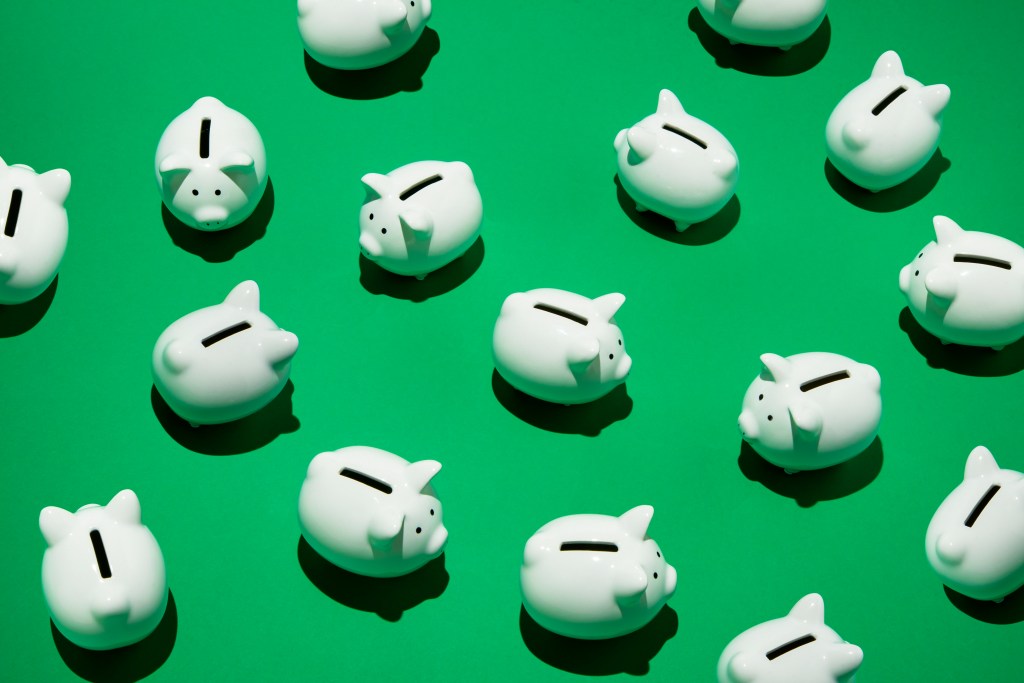 16 small white piggy banks placed randomly on green surface