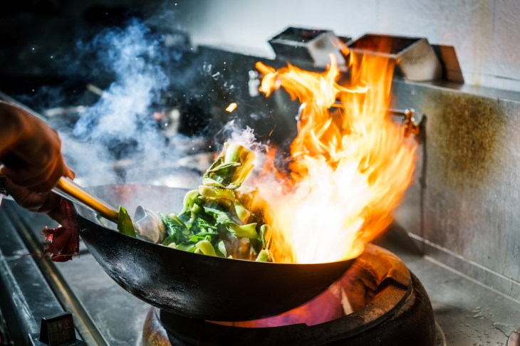 Photo of food being flamed (flambéd) in a wok