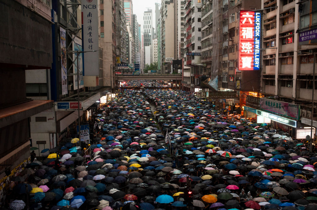 Protesters march while holding umbrellas during the