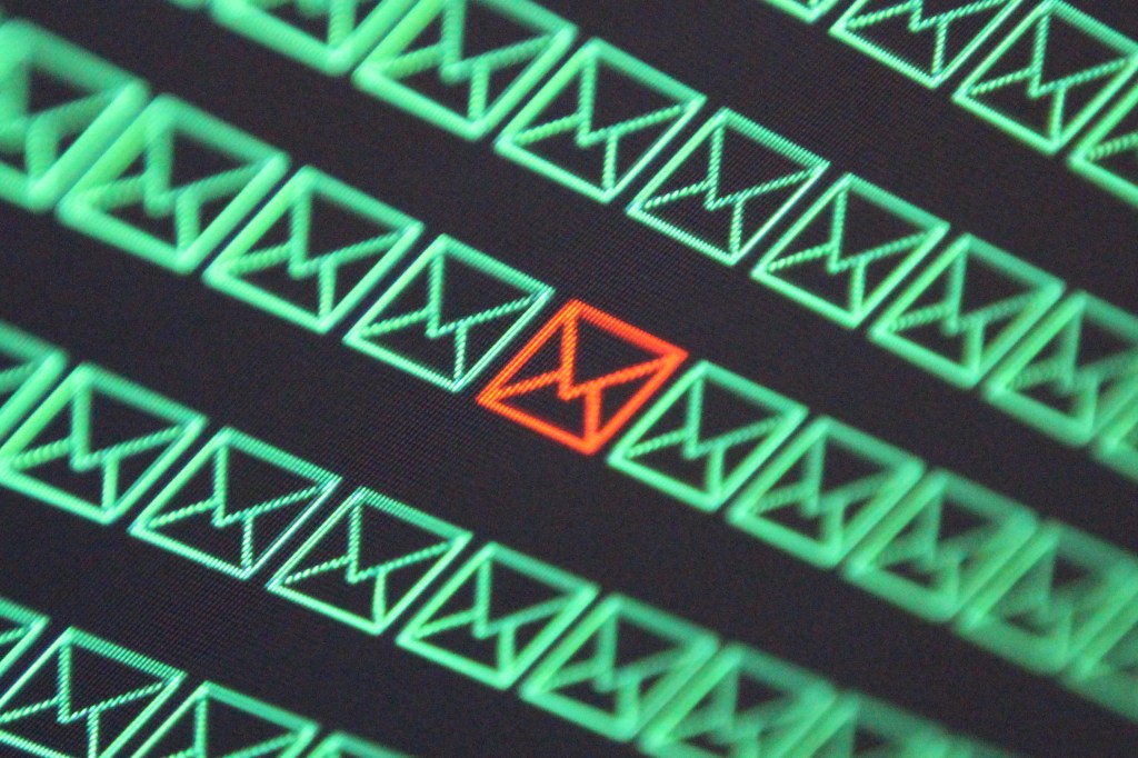 a pattern of green email envelopes on a black background, with a single red email envelope to signify a malicious email
