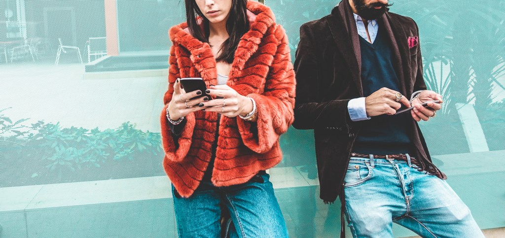 Trendy influencers using smartphone social media app - Young fashion couple watching story video on mobile cell phone - Technology trends, marketing and new digital job concept - Focus on hands
