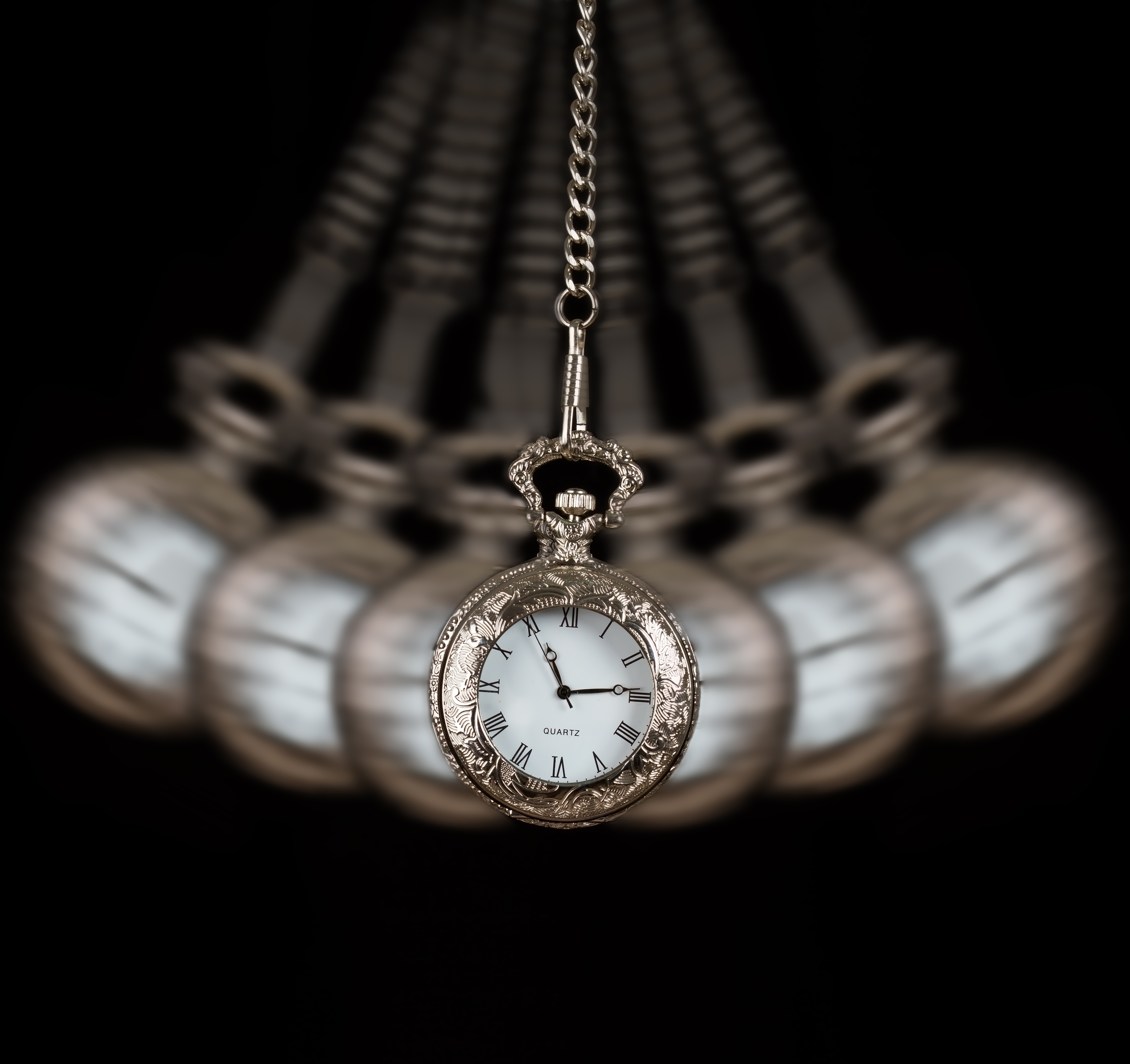 Pocket watch silver swinging on a chain black background to hypnotize