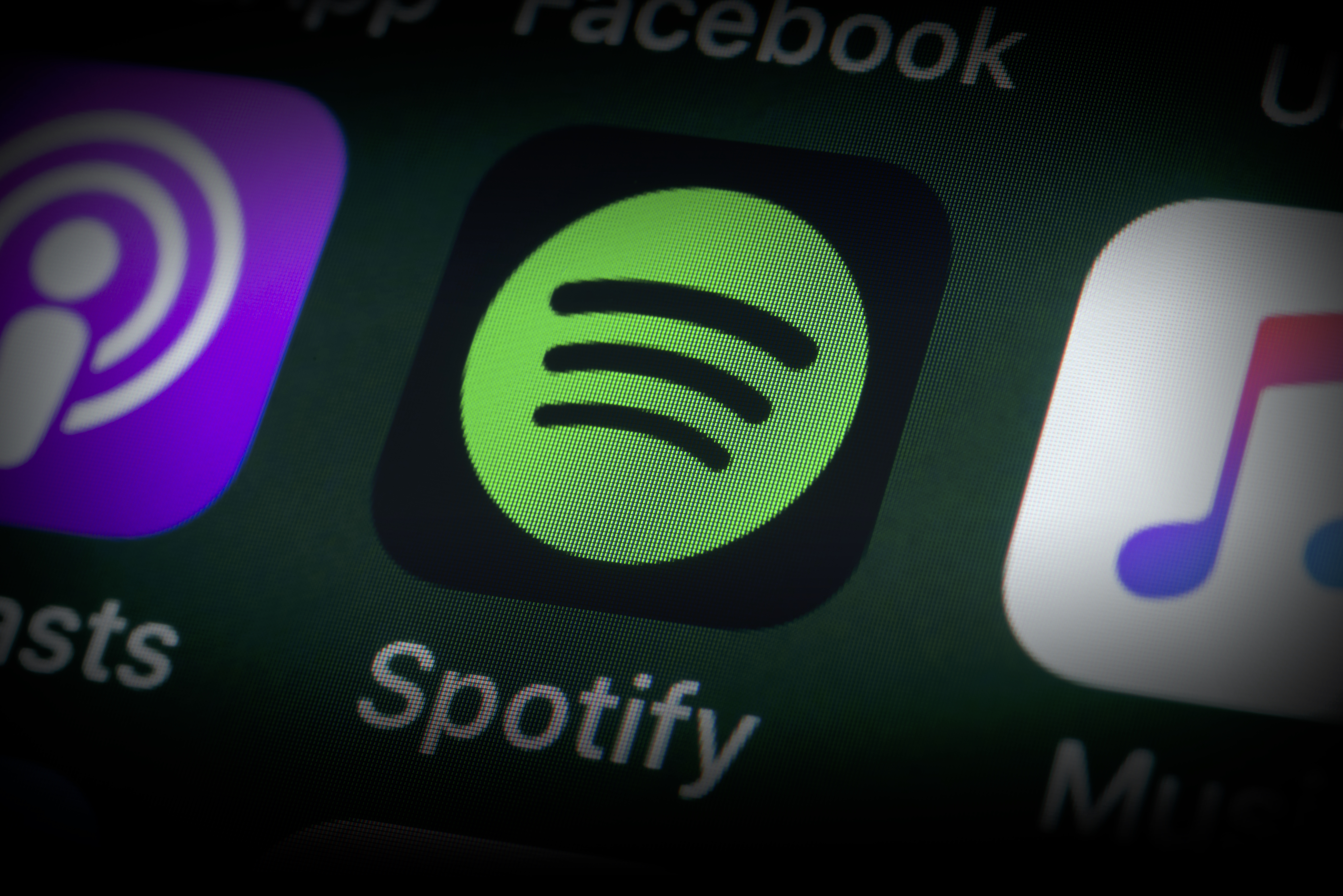 London, UK - July 31, 2018: The buttons of the music streaming app Spotify, surrounded by Podcasts, Apple Music, Facebook and other apps on the screen of an iPhone.