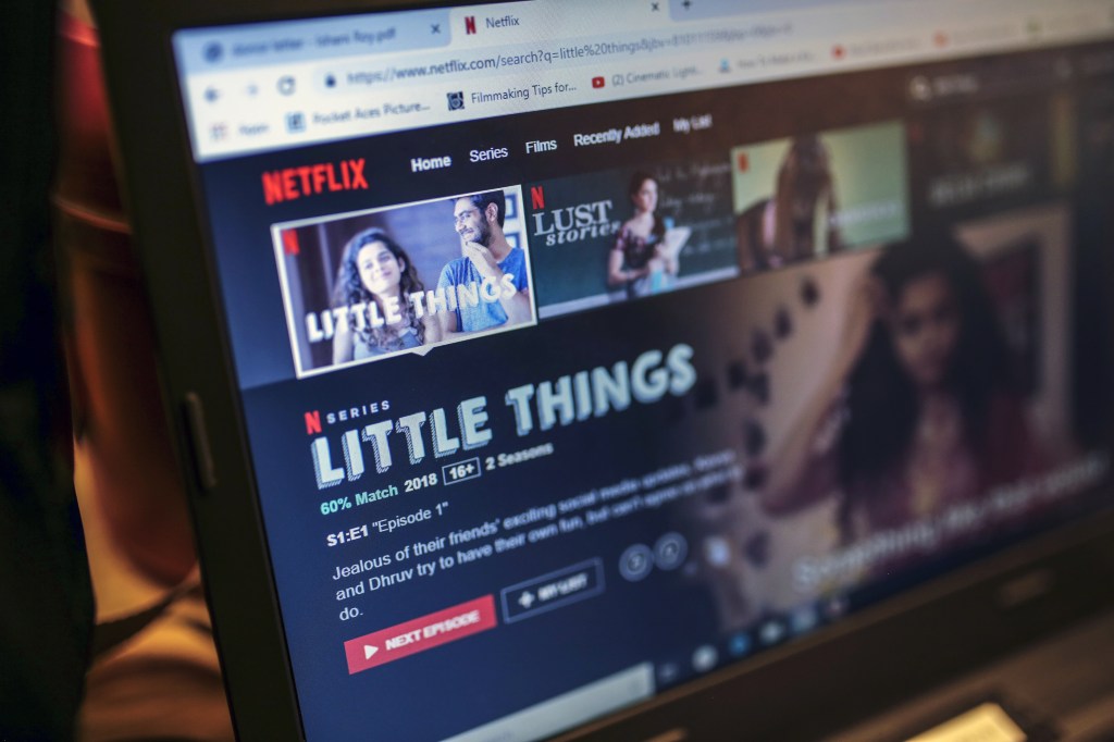A monitor displays a "Little Things" page on the Netflix Inc. website