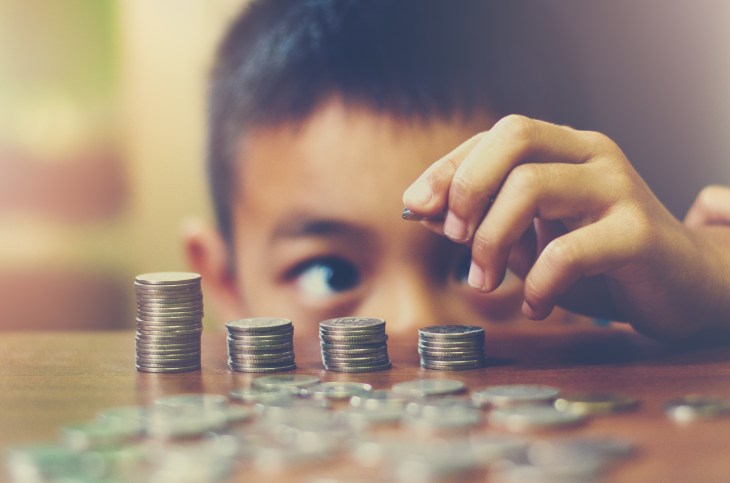Close-Up Of Boy Stacking Coins On Table