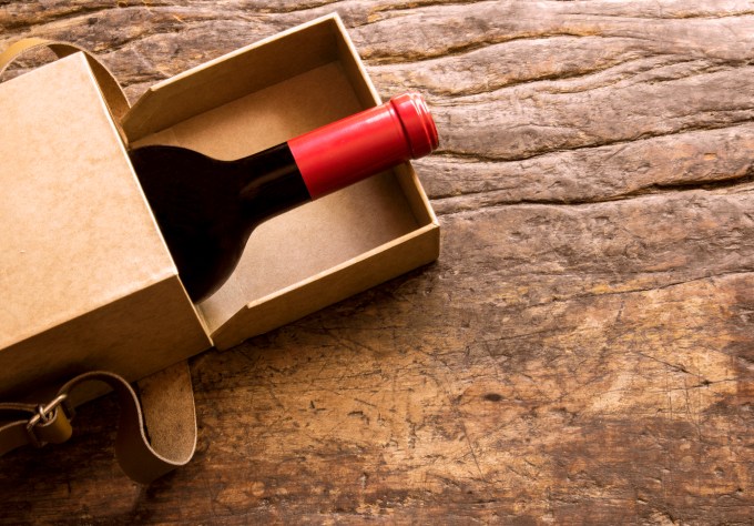 A bottle of wine escaping from a gift box. Still life.