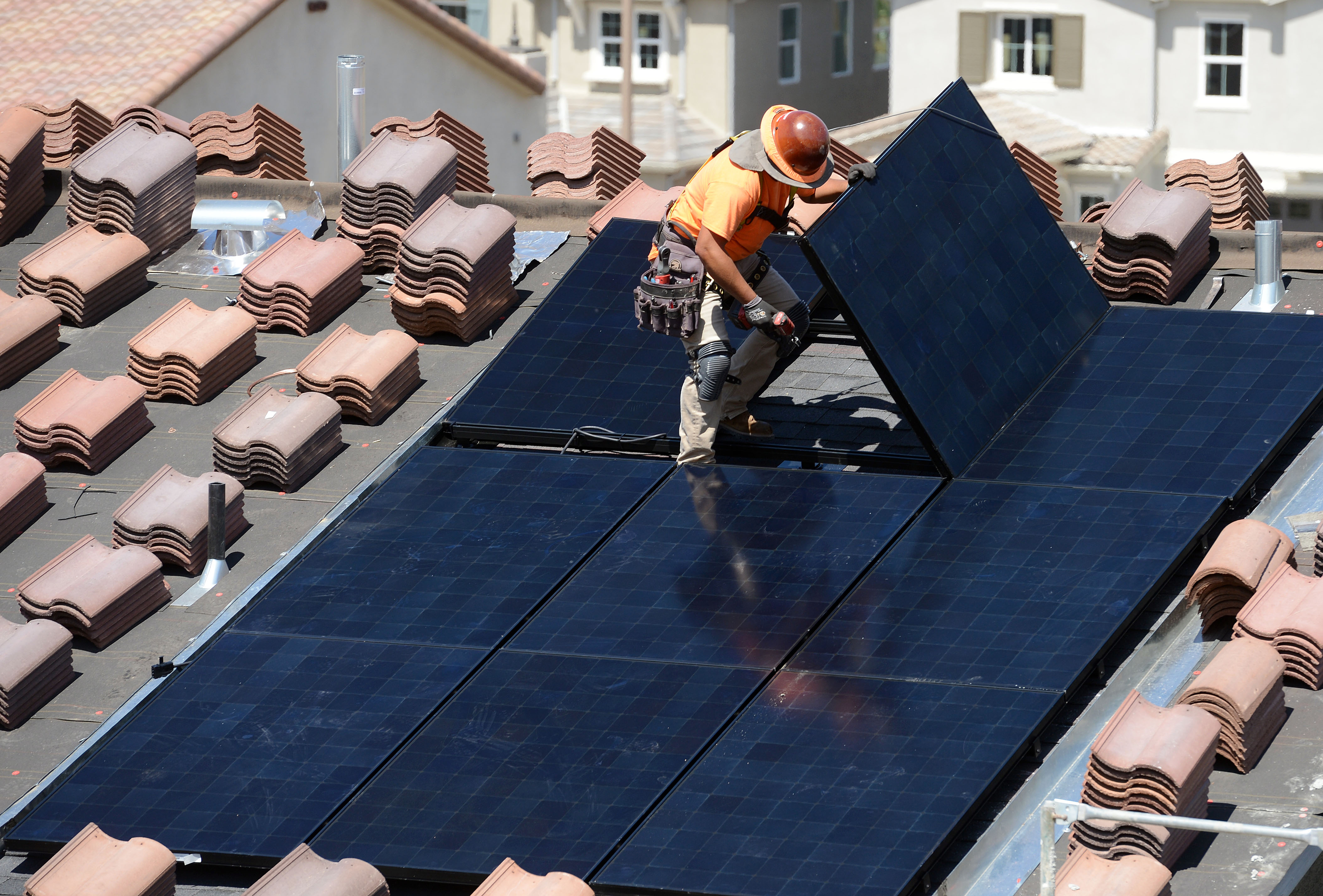 Workers install solar panels on the roofs of homes under construction in California.