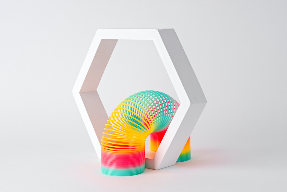 Flexible Multi Colored Coil Crossing Hexagon Frame on White Background.