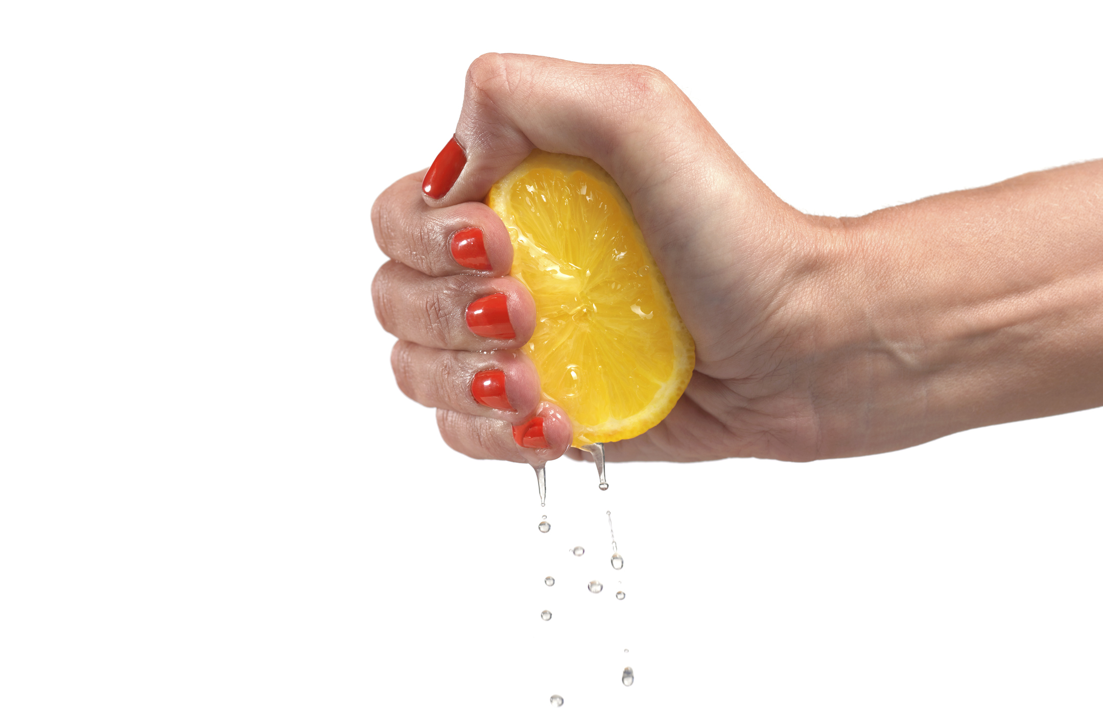 woman wearing red nail varnish squeezing lemon with her hand and drops of lemon juice are falling down