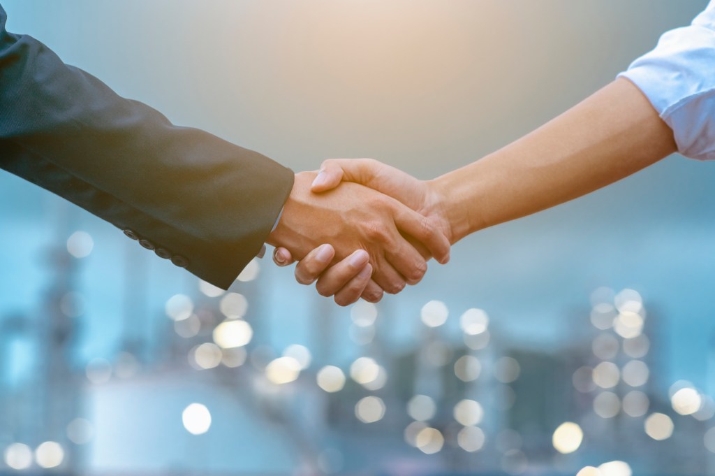 Close-up of two business partners standing and shaking hands they greeting each other during a meeting hand together is a collaborative concept of teamwork for business partners.
