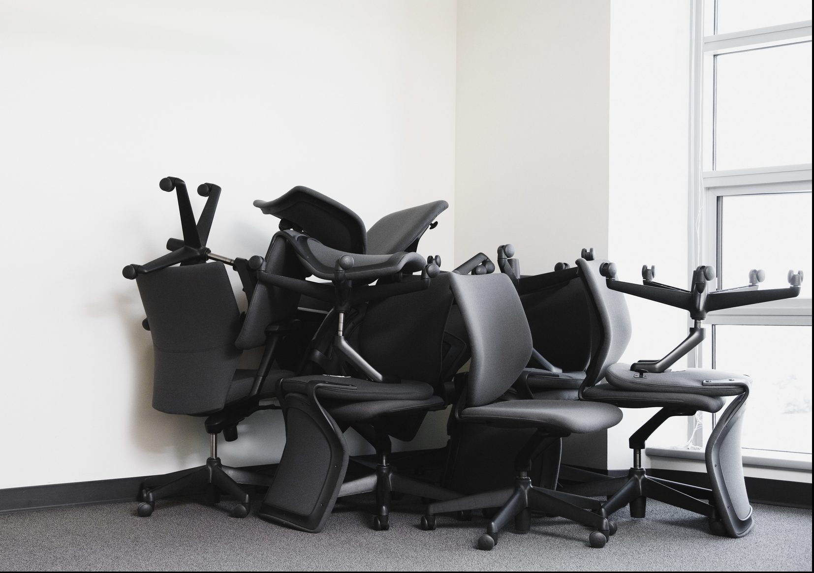 Office chairs are stacked in the corner of an empty office.