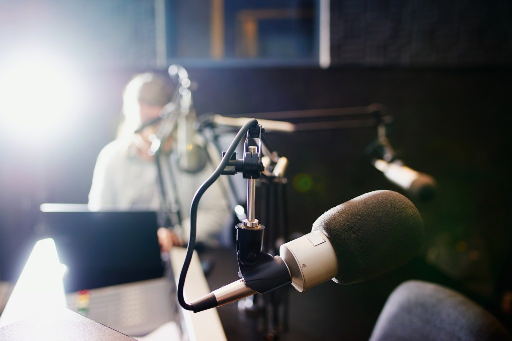 Shot of a microphone in a recording studio with the presenter blurred in the background