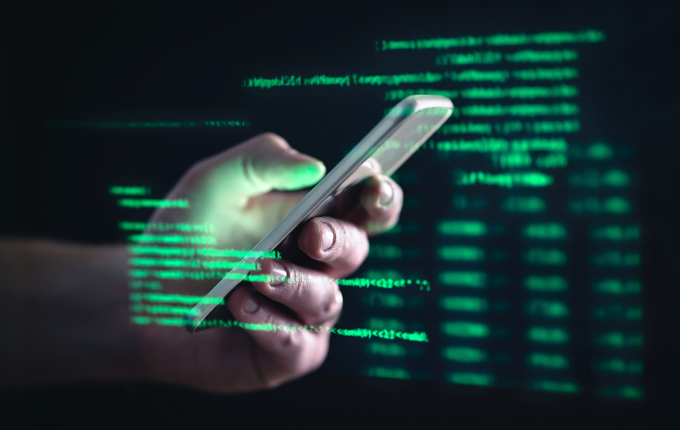 مفهوم Darkweb و darknet والقرصنة.  يد تمسك هاتفًا خلويًا مضافًا إليه نص أخضر على شاشة الكمبيوتر.
