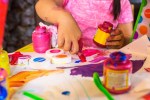Girl sitting at table, making art, using paint, focus on artwork