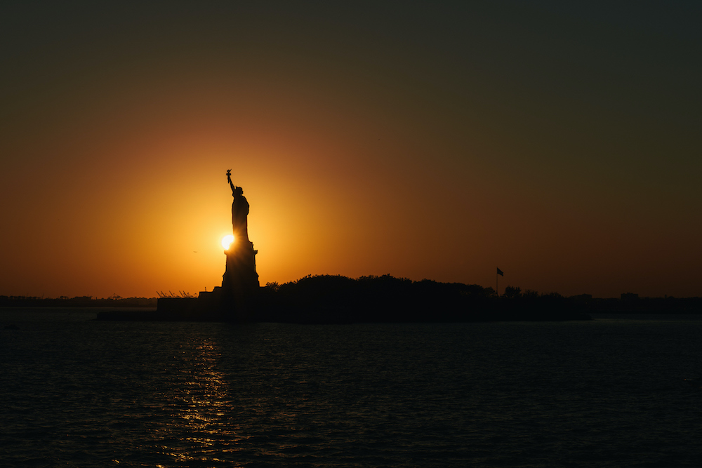 The Statue of Liberty silhouette by the setting sun in New York harbor