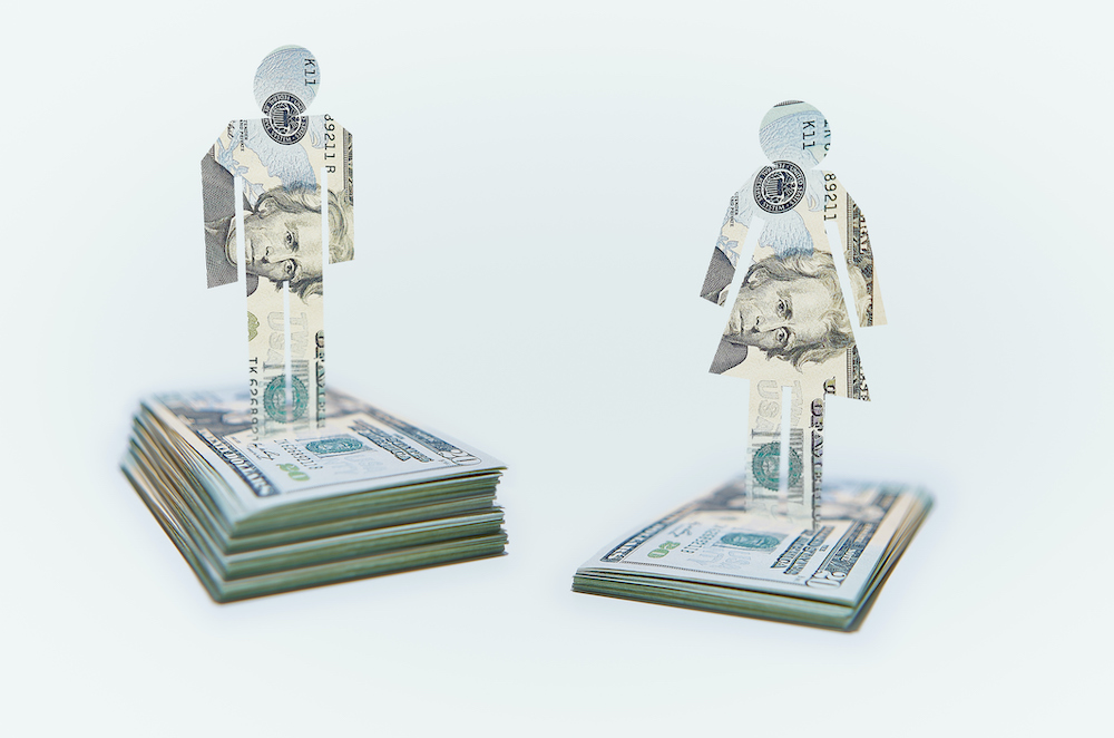 Male and Female Cut-out Figures on top of Bundles of Twenty USD United States Dollar Notes / Bills. Pile of Notes under Female Figure lower than that for the Male Figure.