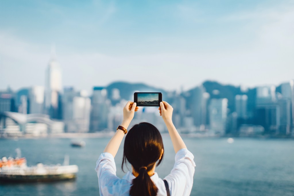 Woman takes photo of Hong Kong's skyline with a smartphone