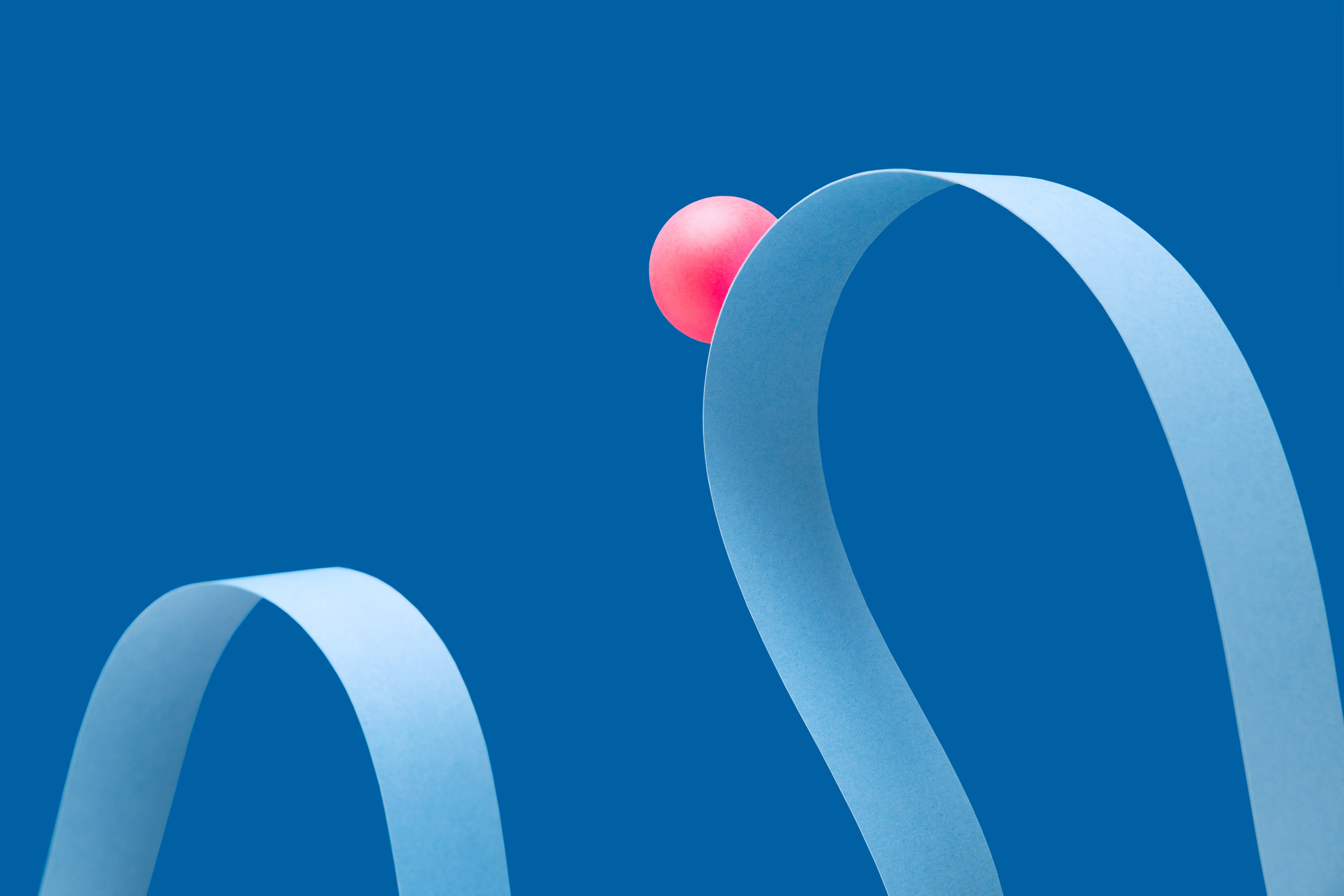 Red ball on curved light blue paper, blue background