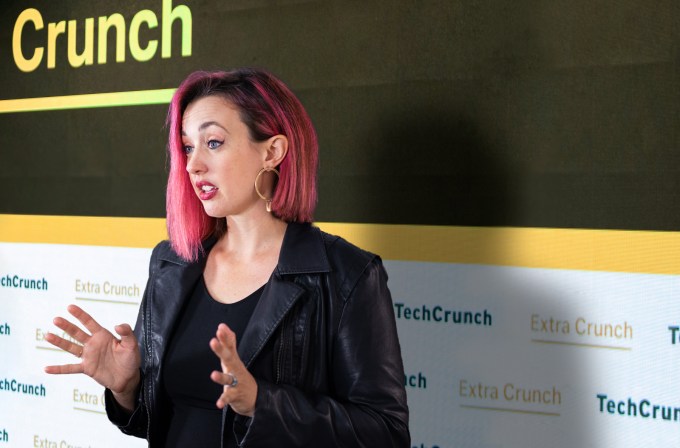 A composite image of immigration law attorney Sophie Alcorn in front of a background featuring a TechCrunch logo.