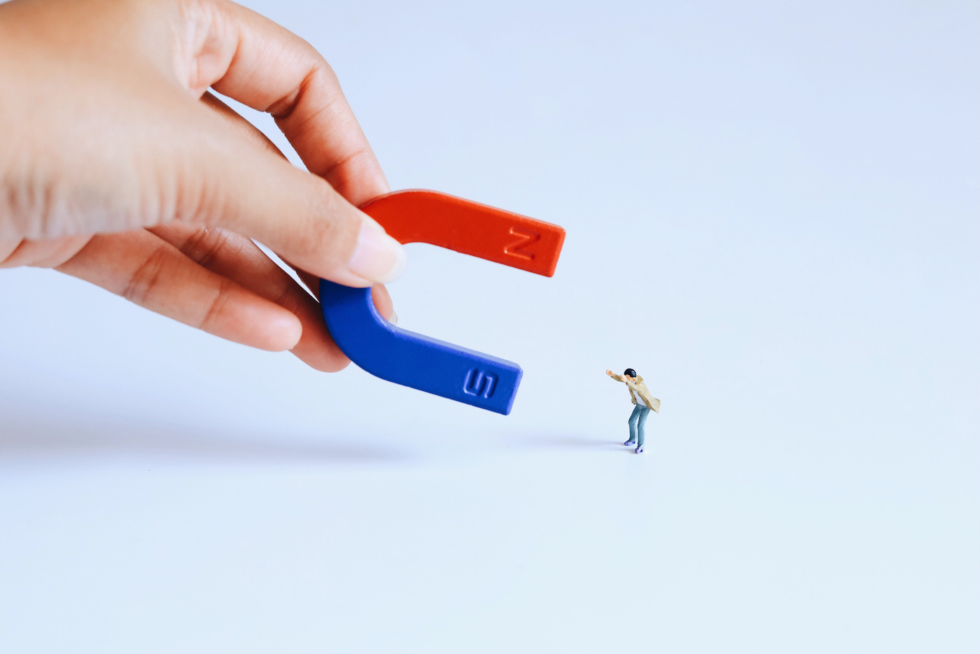 Cropped Hand Holding Magnet Toy Against White Background