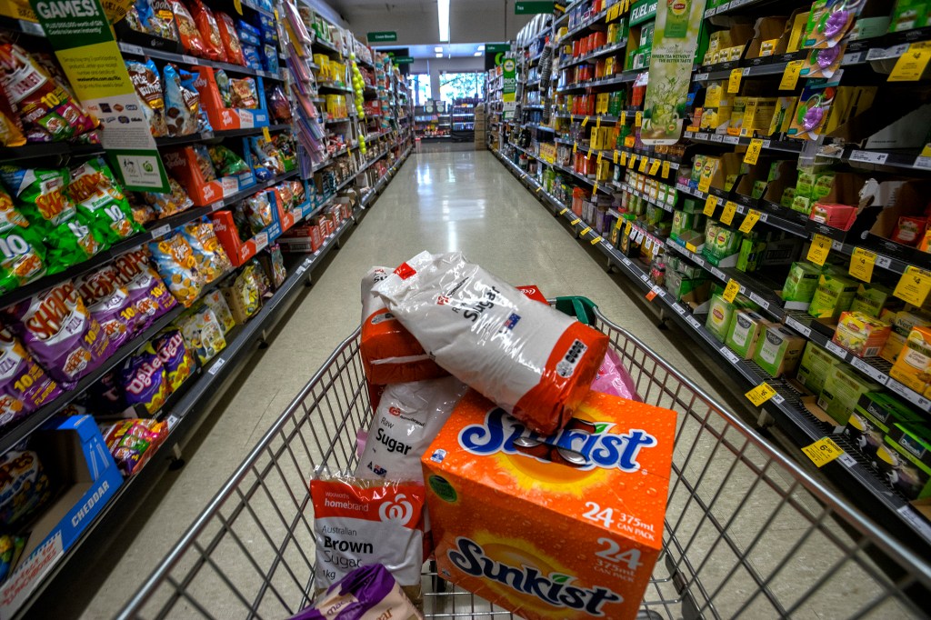 POV shopping cart with items rolling down grocery aisle.