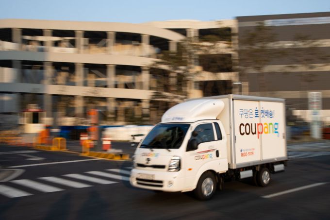A Coupang Corp. delivery truck drives past a company's fulfillment center in Bucheon, South Korea, on Friday, Feb. 19, 2021. South Korean e-commerce giant Coupang filed for an initial public offering in the U.S. and that could raise billions of dollars to battle rivals and kick off a record year for IPOs in the Asian country. Photographer: SeongJoon Cho/Bloomberg via Getty Images
