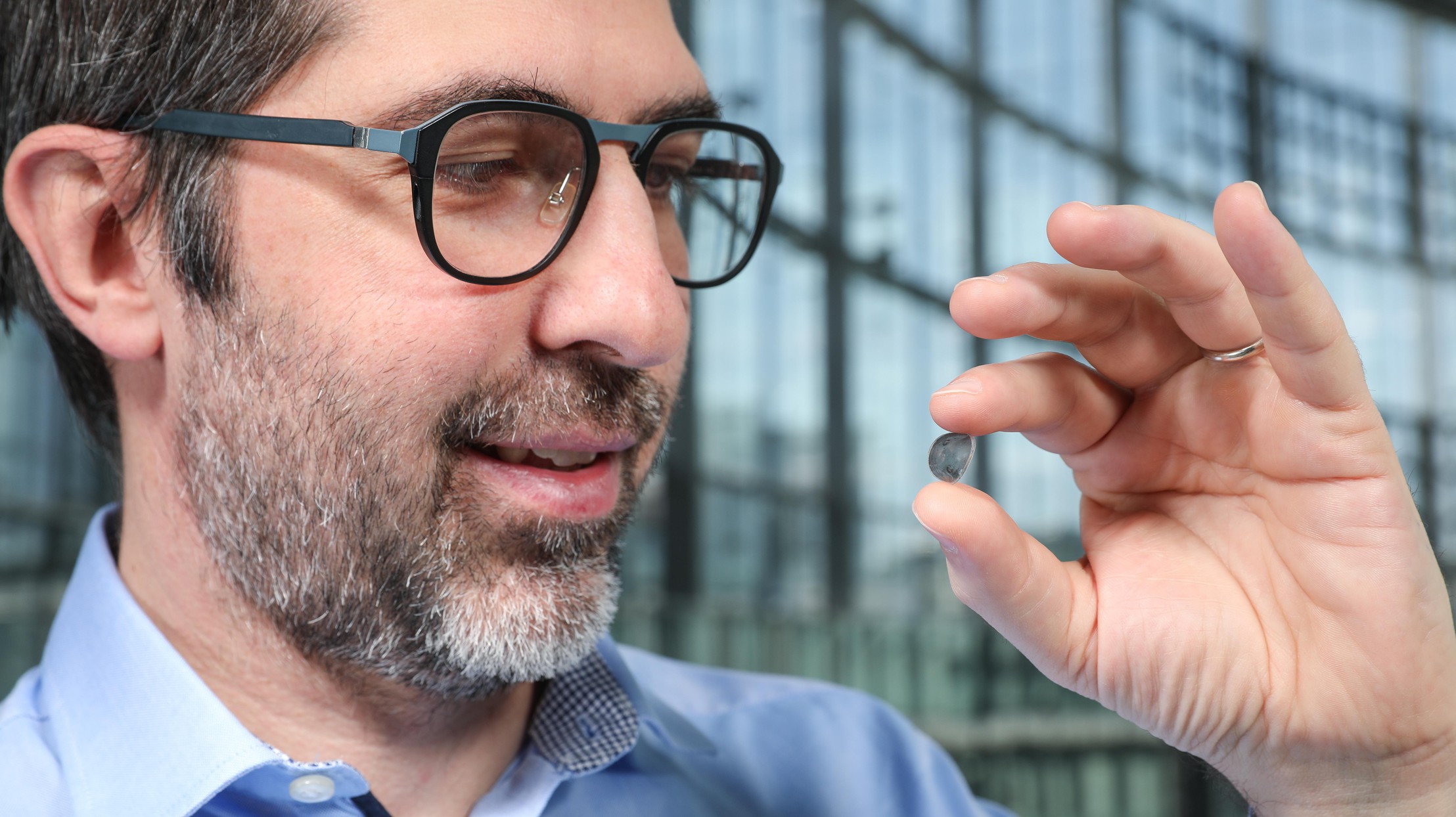 Researcher Diego Ghezzi holds a contact lens with photovoltaic dots on it.