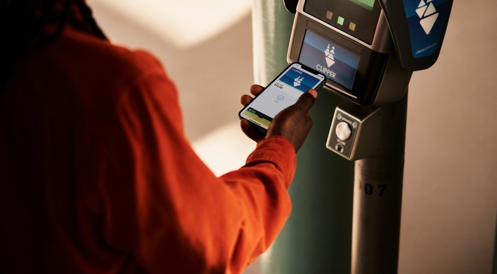 Someone using an iPhone to pay for transit at a Clipper card reader