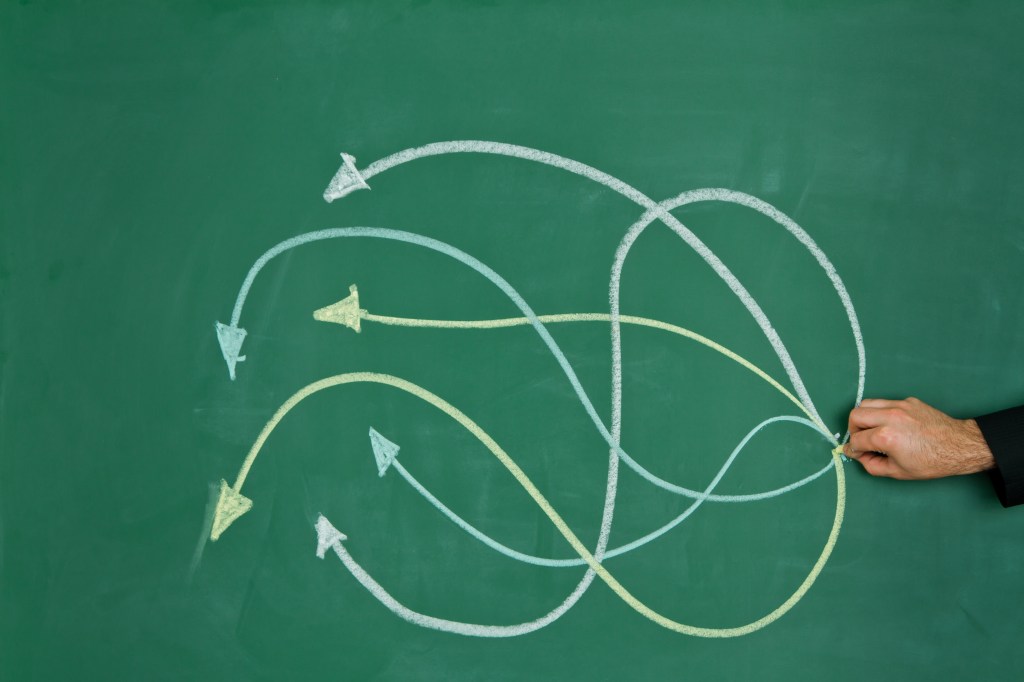 Image of intertwining arrows on a chalkboard to represent decision-making.