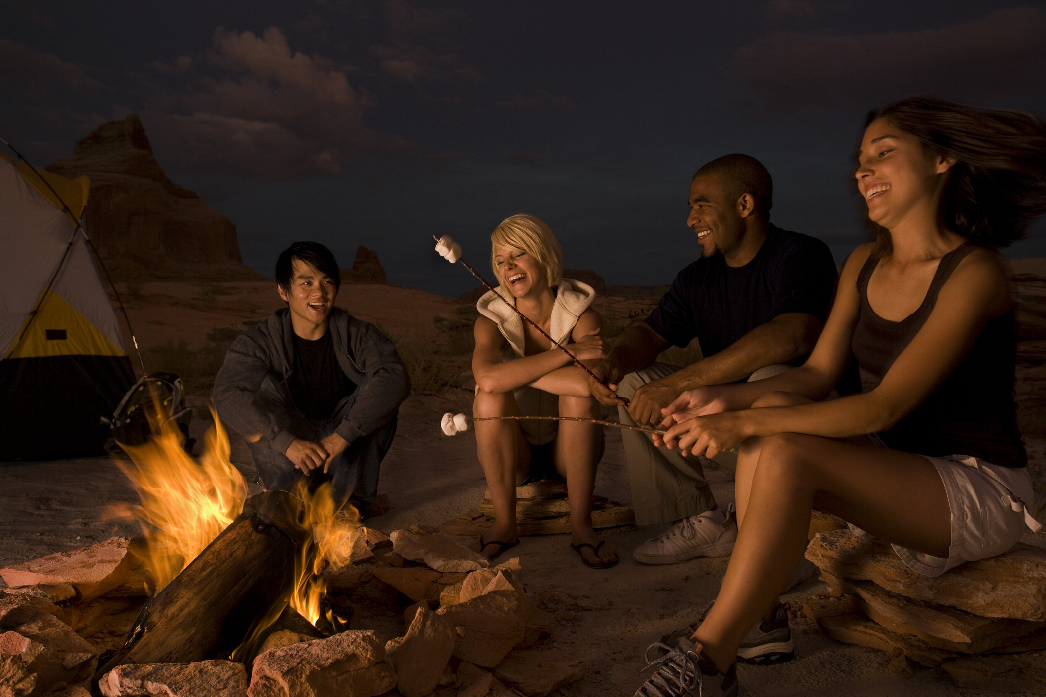 Two couples sitting by a campfire
