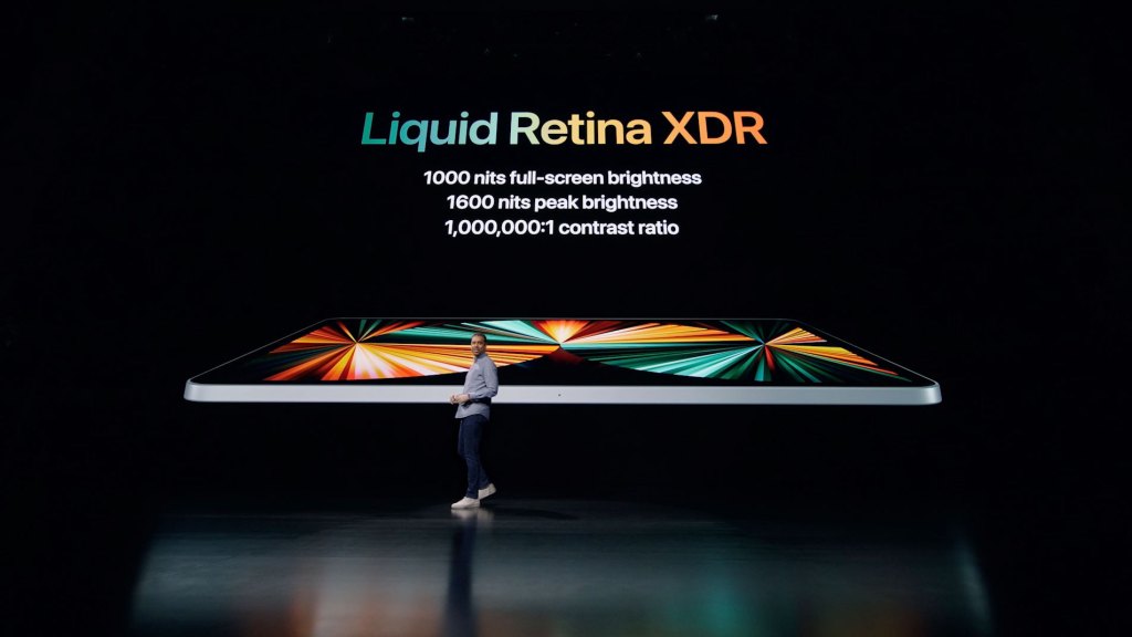 presenter in front of screen with iPad Pro 2021, text reads Liquid Retina XDR, 1000 nits full-screen brightness, 1600 nits peak brightness, 1,000,000:1 contrast ratio