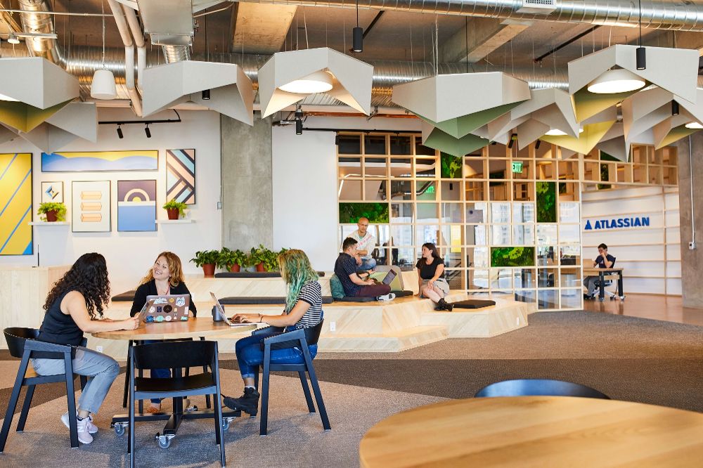 Atlassian office with three people working at a table in the foreground.