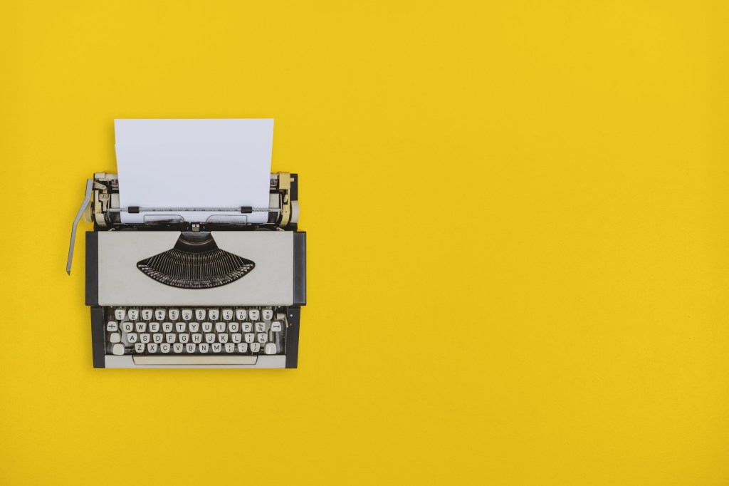 Overhead view of old typewriter on yellow background.