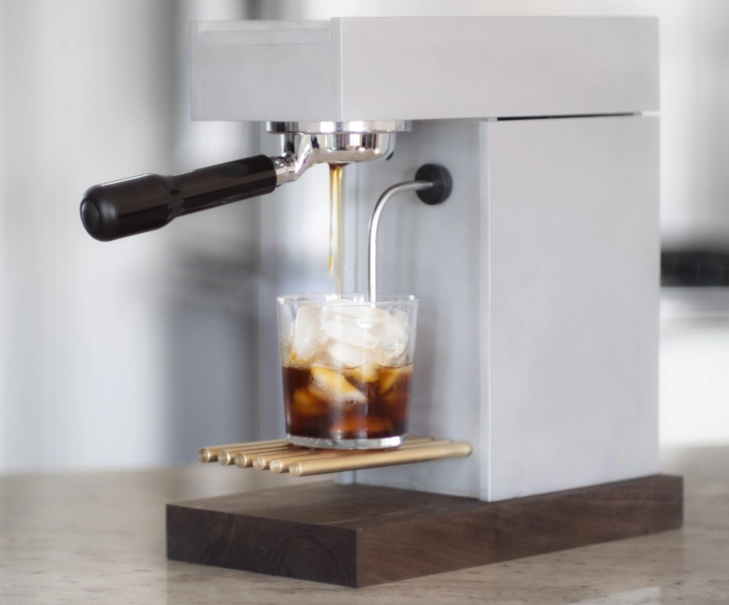 An Osma machine making coffee in a glass filled with ice.