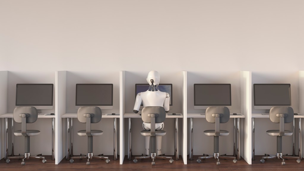 Image of a robot sitting alone in a row of five cubicles to represent AI aiding the US labor shortage.