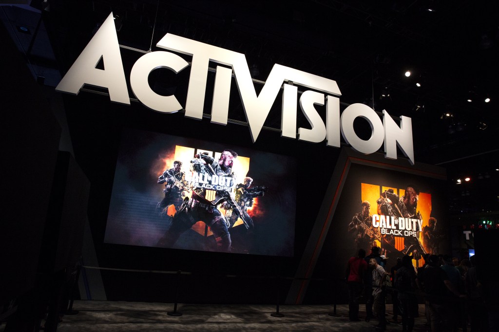 Participanții stau lângă indicatoarele pentru Activision Blizzard Inc.