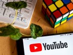 photo illustration of a YouTube logo displayed on a smartphone next to a rubik's cube, a computer keyboard and a leaf.