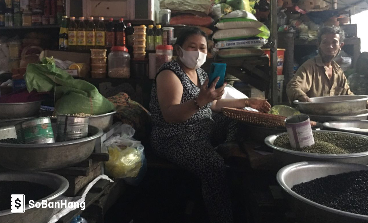 Une photo d'un marchand au Vietnam regardant un smartphone