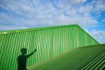 Shadow of anonymous man on green metal construction in sunlight