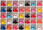 Many different colored rubber ducks sit in wooden pigeon hole compartments. Concept image regarding different ethnicity/gender people living together in harmony together in the same social environment, getting along together, living side by side.