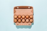 Organic eggs in cartons tray on blue background. Flat lay, top view