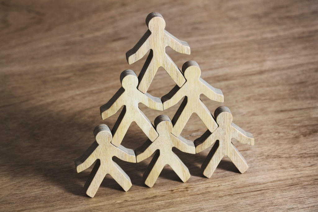 Six wooden model men standing in pyramid formation