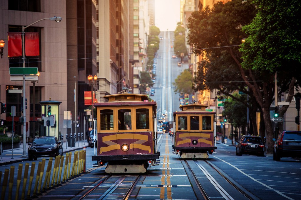 Classic view of historic traditional Cable Cars riding on famous California Street in beautiful early morning light at sunrise in summer with retro vintage style cross processing filter effect, San Francisco, California, USA (Classic view of historic